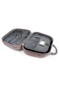 Maleta de mano de carcasa rígida en rosa, con un interior acolchado gris que incluye compartimentos y correas elásticas. Cierre de cremallera, incluye asa superior.