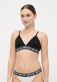 Bralette triangle noire avec des bretelles réglables et une large bande présentant le texte "justcavalli" en blanc ; assortie à un bas de bikini blanc.
