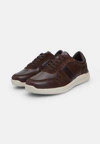 Barna bőr sneaker, texturált velúr betéttel, párnázott talppal és sötét cipőfűzőkkel. Stílusos dizájn kontrasztos színekkel.