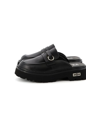Scarpe slip-on nere con piattaforma realizzate in pelle liscia, dotate di una fascia con un anello metallico, suola texturizzata e un'accento con il marchio sul lato.