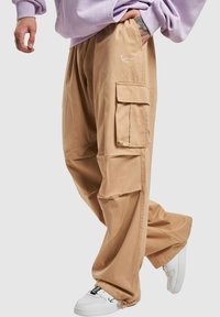 Beige cargo bukser med en afslappet pasform, der har sidelommer og broderet logodetalje. Materialet fremstår glat og let.