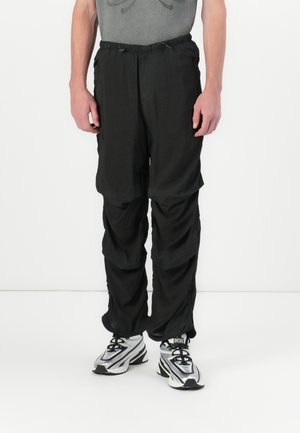 Black lightweight pants with a loose fit, featuring an elastic waistband and drawstring, gathered seams, and a smooth texture.