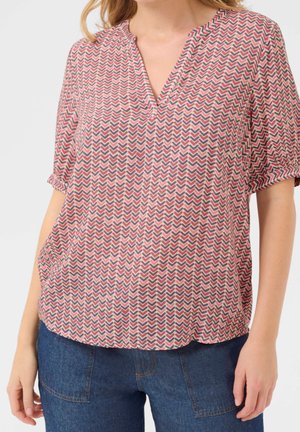 Blouse à manches courtes avec un décolleté en V, présentant un motif zigzag rose et bleu marine sur un tissu léger, avec un ourlet arrondi et une coupe décontractée.