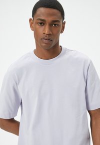 Lys lavendel bomuld t-shirt med rund halsudskæring og korte ærmer, der har en glat tekstur og en afslappet pasform.