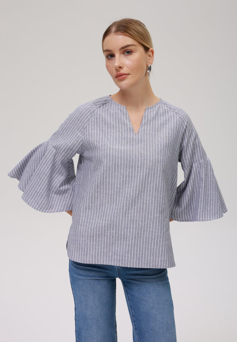 Stripet bluse i grått og hvitt stoff, med V-hals, tre-kvart ermer med bjelleform og avslappet passform. Glatt tekstur og lett design.