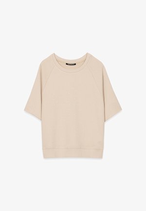 Beige short-sleeve sweatshirt with small silver dot embellishments and a ribbed hem and neckline, flat lay on white background.