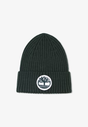 Bonnet côtelé vert foncé avec un revers. Présente un patch circulaire blanc avec un logo d'arbre à l'avant. Texture en tricot douce.