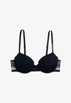 Brasiletta imbottita nera con dettagli in pizzo sui lati, spalline regolabili e un tessuto liscio e testurizzato. Presenta un design con coppe tonde.