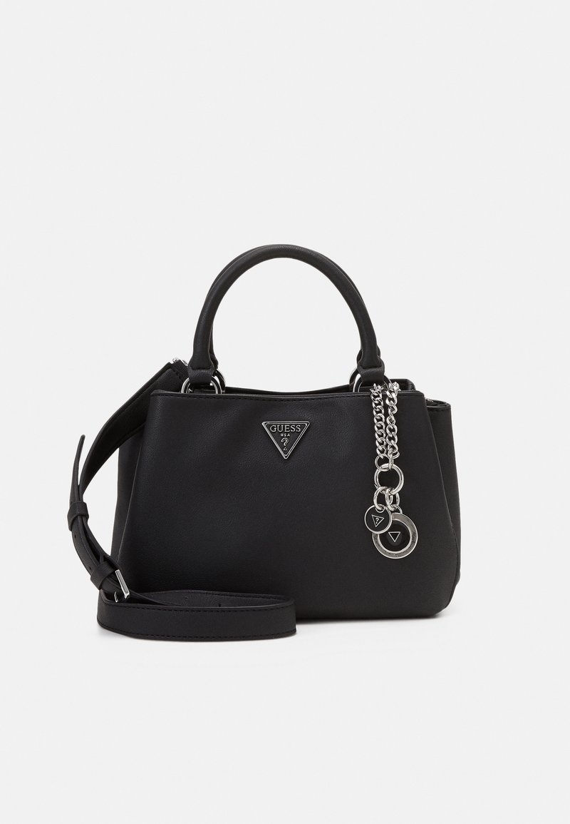 Sac à main Guess en cuir noir avec poignées courtes, bandoulière amovible et pendentif logo argenté suspendu sur le côté avant.