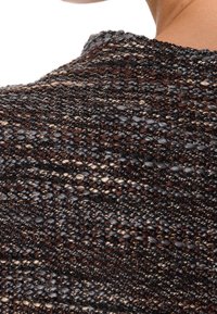 Détail d'un pull en maille présentant un mélange de bruns foncés, de gris et de fils métalliques, mettant en valeur une texture à tissage ouvert et un col arrondi.