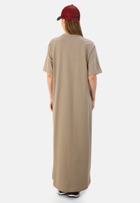 Beige maxi dress with short sleeves, relaxed fit, and smooth texture. Paired with a red cap featuring a mesh design.