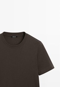 Mørkebrunt T-shirt med rund halsudskæring, korte ærmer og ribbet tekstur. Indeholder et label med brandnavn ved halsudskæringen.