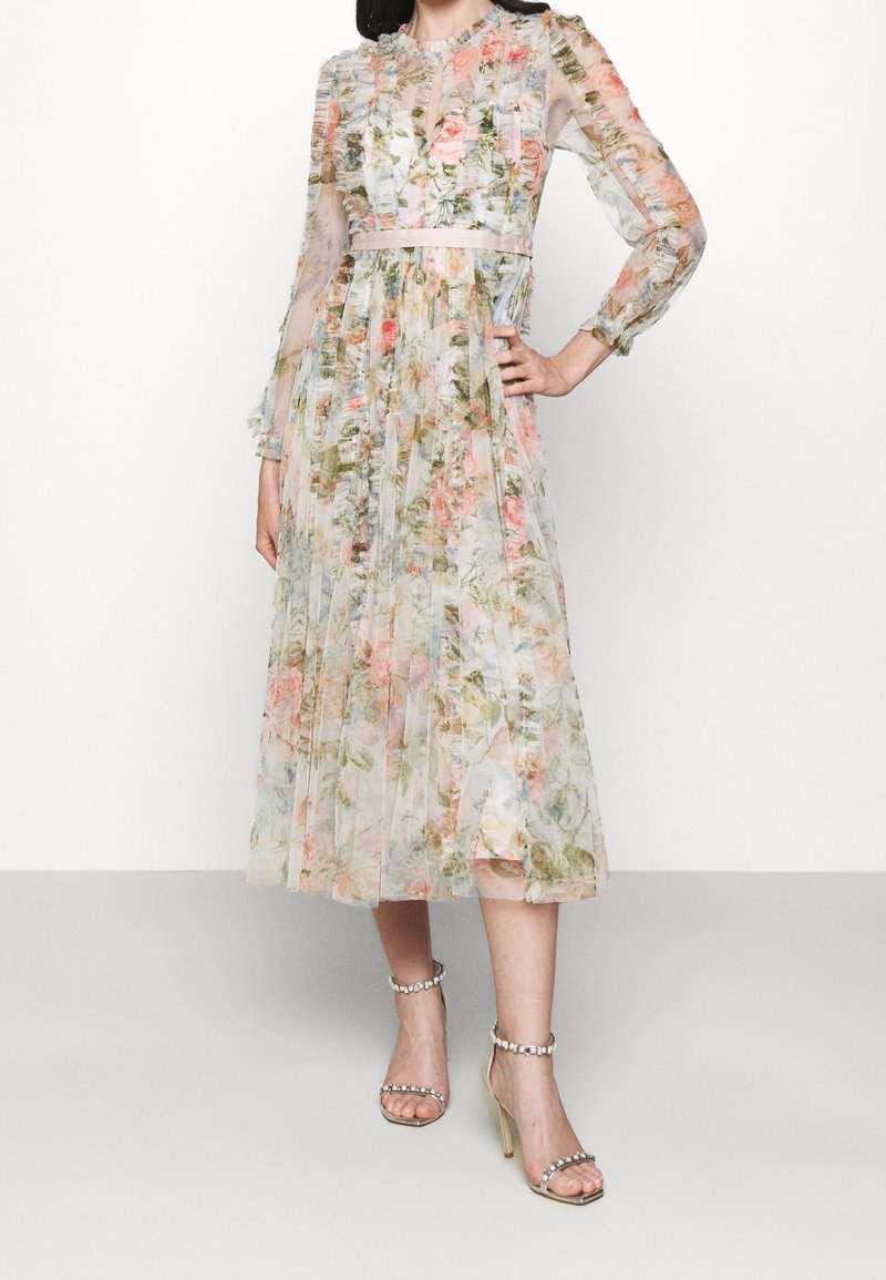 Robe légère à fleurs avec manches longues, motif plissé et taille cintrée. Présente des couleurs pastel et un détail subtil d'encolure en forme de goutte.