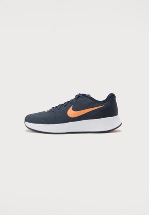 Tmavě modrá běžecká bota Nike s oranžovým logem swoosh, bílou mezipodešví a černou podrážkou, zobrazena z levé strany na jednoduchém pozadí.