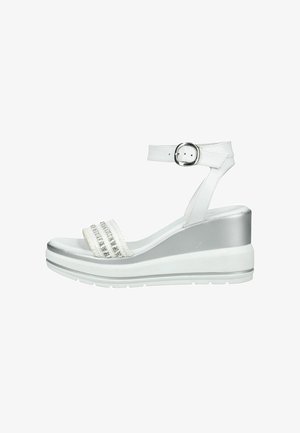 Sandalia de cuña blanca con correa en el tobillo, hebilla plateada y correa frontal decorada con cuentas plateadas y bandas blancas con textura.