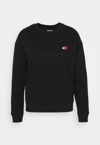 Sudadera negra con cuello redondo, mangas largas y puños de canalé. Presenta un pequeño logo coloreado en el pecho. Textura de tela suave.