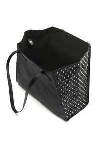 Tote bag en cuir noir avec des clous argentés sur un côté, un haut ouvert et deux poignées. L'intérieur est non doublé avec une finition texturée.