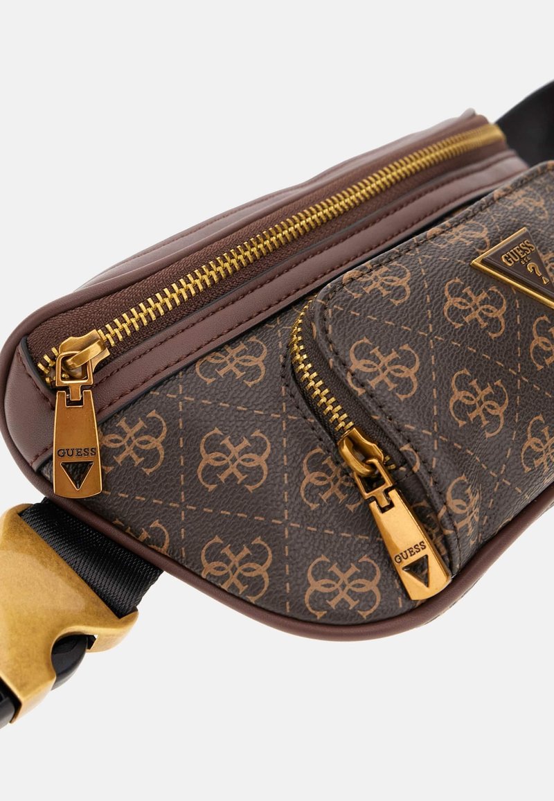 Sac banane Guess marron à motifs avec fermetures éclair dorées et logo, comportant deux compartiments zippés et une sangle noire réglable avec boucle dorée.