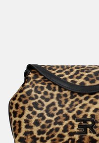 Borsa a tracolla con stampa leopardata, caratterizzata da una finitura testurizzata simile alla pelliccia, con dettagli in pelle nera e un logo metallico sulla parte anteriore.