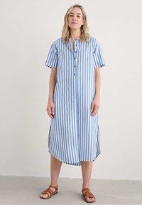 Abito camicia con bottoni, maniche corte, caratterizzato da righe verticali blu e bianche, lungo fino al ginocchio, con spacchi laterali e una vestibilità comoda.
