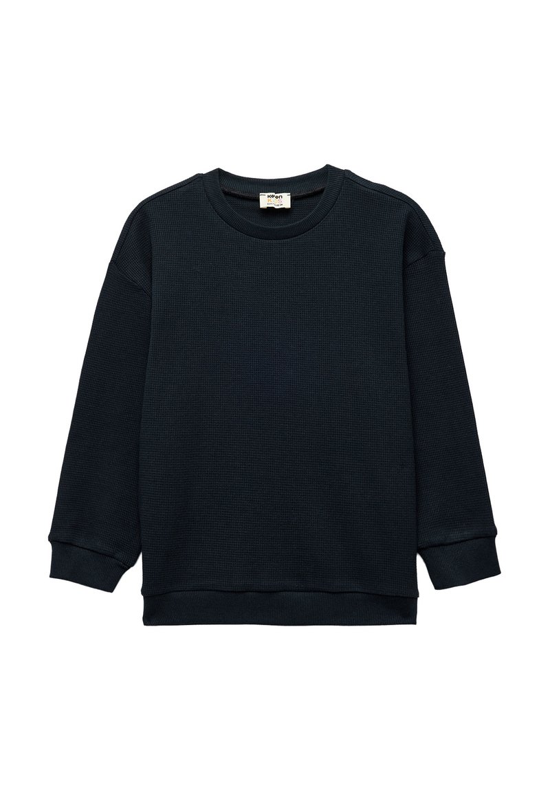 Sudadera negra de textura tipo waffle con mangas largas, cuello redondo y puños acanalados. Diseño minimalista, sin patrones ni acentos visibles.