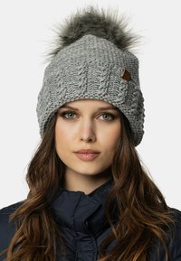 Szary, dziany beanie z wzorem w warkocze, z puszystym szarym pomponem na górze i małą skórzaną metką w kolorze brązowym.
