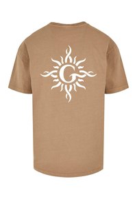 Lys beige kortærmet t-shirt med et hvidt solmotiv og et centralt "G" logo på ryggen. Fremstillet af blødt, letvægts stof.