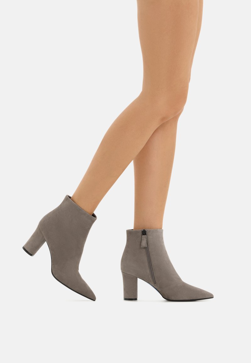 Stivaletti alla caviglia grigi in suede con punta appuntita e zip laterale. Presentano un tacco spesso e una texture liscia.
