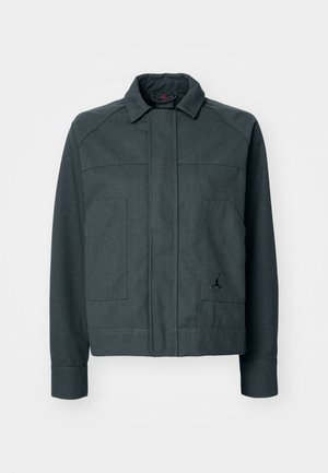 Dunkelgraue Jacke mit Kragen, Frontreißverschluss, zwei großen Taschen und einem kleinen Logo in Schwarz auf der linken Seite. Aus einem Baumwollmischgewebe.