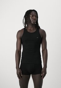 Black sleeveless tank top and matching shorts, fitted design, made of smooth fabric. Minimal branding detail on the top.