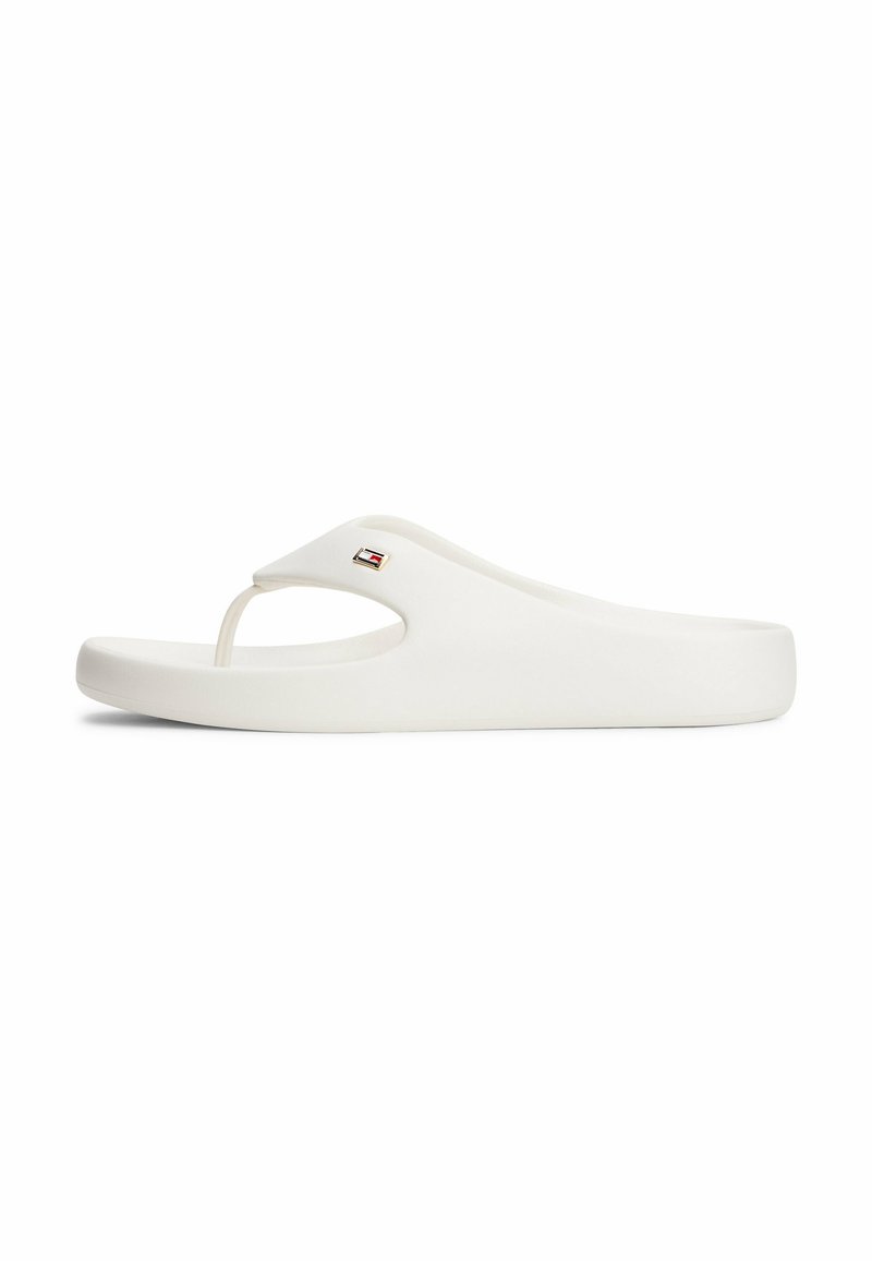Chancla blanca hecha de goma suave con una tira en forma de V y un pequeño logotipo en la parte superior. Diseño ligero y minimalista.