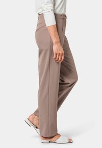 Lichtbruine op maat gemaakte broeken met een rechte pasvorm, met een gladde textuur en een tailleband met een knoopsluiting, gedragen met witte slipper-sandalen.
