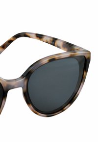 Lunettes de soleil en forme de œil de chat avec un motif écaille de tortue, des verres teintés foncés et des montures en polycarbonate avec une finition brillante.