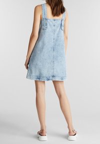 Jeanimekko vaaleansinisessä värissä, jossa on leveät olkaimet, suora siluetti ja helma polven yläpuolella. Rypytetty kangas näkyvillä saumoilla.