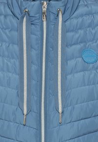 Blaue gepolsterte Jacke mit gesteppter Optik, silbernem Reißverschluss und glitzernden Kordeln. Verfügt über ein rundes Logo auf dem Stoff.