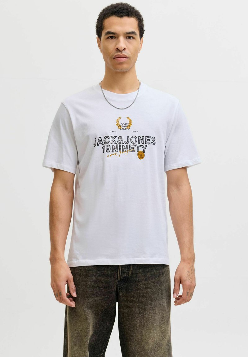 Camiseta de algodón blanca con texto gráfico en negro y dorado "JACK&JONES 19NINETY" con un diseño de laurel, mangas cortas y un corte relajado.