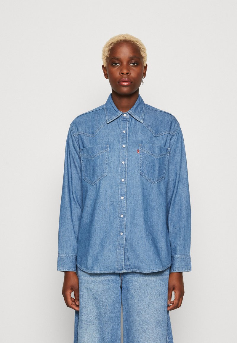  Lichtblauw denim shirt met een kraag, lange mouwen, twee voorzakken en knoopsluiting met stiksels.