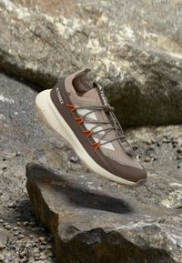 Chaussure de randonnée légère en marron et beige, avec une tige en mesh, des accents texturés, des lacets orange et une semelle coussinée de couleur crème.