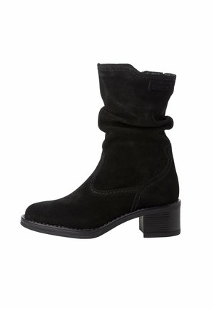 Botte noire en daim mi-mollet avec tige plissée, bout arrondi, coutures décoratives et talon bloc bas sur fond blanc.