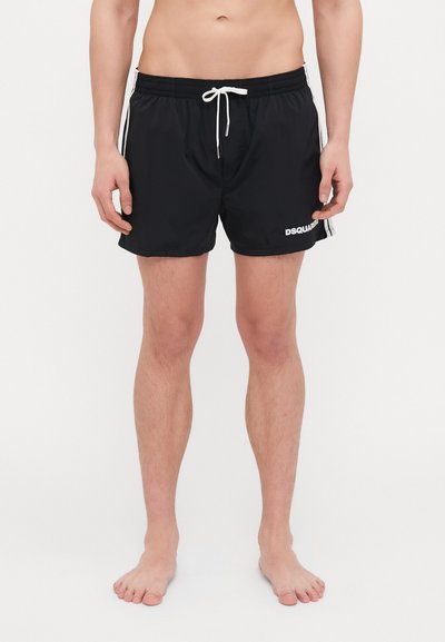 Pantaloni da bagno neri realizzati in tessuto leggero, dotati di una cintura elastica con coulisse bianca e un logo sul lato sinistro in basso.