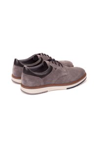 Chaussures en daim grises avec des accents en cuir noir, lacets ronds, semelle blanche et garniture marron, présentant une texture lisse et un design classique.