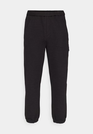 Black jogger pants made of textured fabric. Features an elastic waistband, side pockets, and elastic cuffs at the ankles.