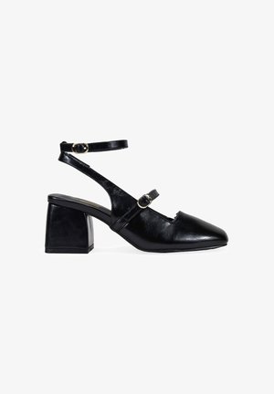 Black leather block-heeled sandals with pointed toe, dual ankle straps featuring gold-tone buckles, and a smooth texture.