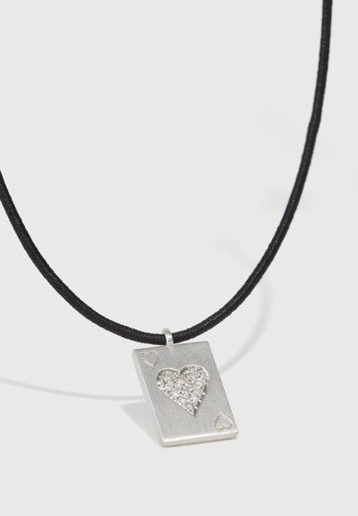 Pendentif en argent en forme de carte à jouer avec un motif de cœur, orné de strass transparents ; sur un collier en cordon noir.
