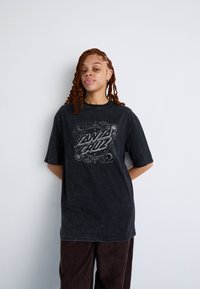 Tricou oversize negru cu un imprimeu grafic cu "Santa Cruz" într-un design decorativ. Material texturat cu un finisaj deteriorat.