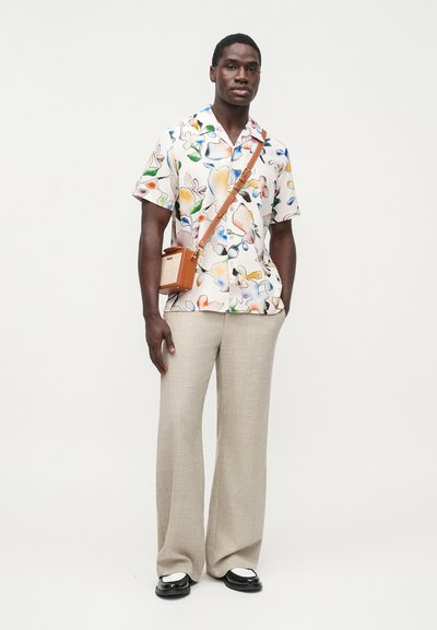 Κοντομάνικο πολύχρωμο πουκάμισο με λουλούδια, σε συνδυασμό με μπεζ, άνετο παντελόνι. Αξεσουάρ περιλαμβάνουν μια μικρή καφέ τσάντα χιαστί. Μαύρα παπούτσια.