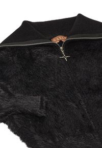 Zwarte zip-up jack met een zachte faux fur buitenkant, hoge kraag en zilveren hardware details op de rits. De voering is van een gladde zwarte stof.