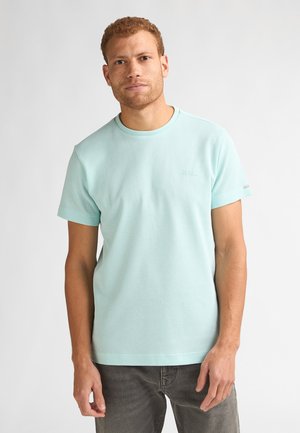 Lichtblauw T-shirt met korte mouwen, een geribbelde textuur en een ronde hals. Voorzien van subtiele branding, gecombineerd met donkergrijze broek.