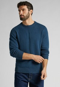 Blauwe crewneck trui van zacht materiaal, met ribgebreide manchetten en onderrand. De trui heeft een losse pasvorm en een textuurgebreid ontwerp.