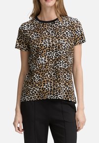 T-shirt imprimé léopard en marron, noir et blanc. Manches courtes, col rond avec un bord noir, coupe décontractée et texture douce.